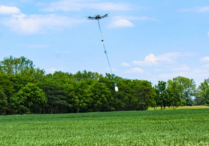 Drone flying over an Ohio soybean field with stinger platform suspended beneath.